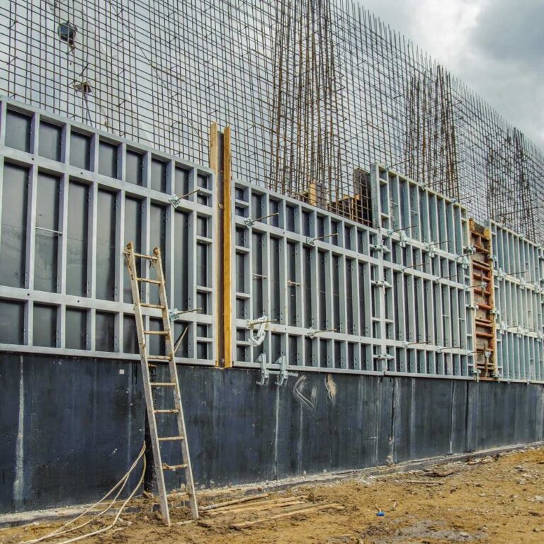 Reinforced cast in-situ concrete retaining wall under construction with formwork and exposed rebar