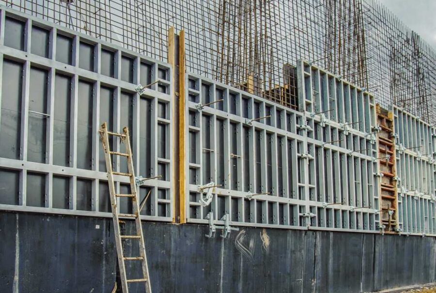 Reinforced cast in-situ concrete retaining wall under construction with formwork and exposed rebar
